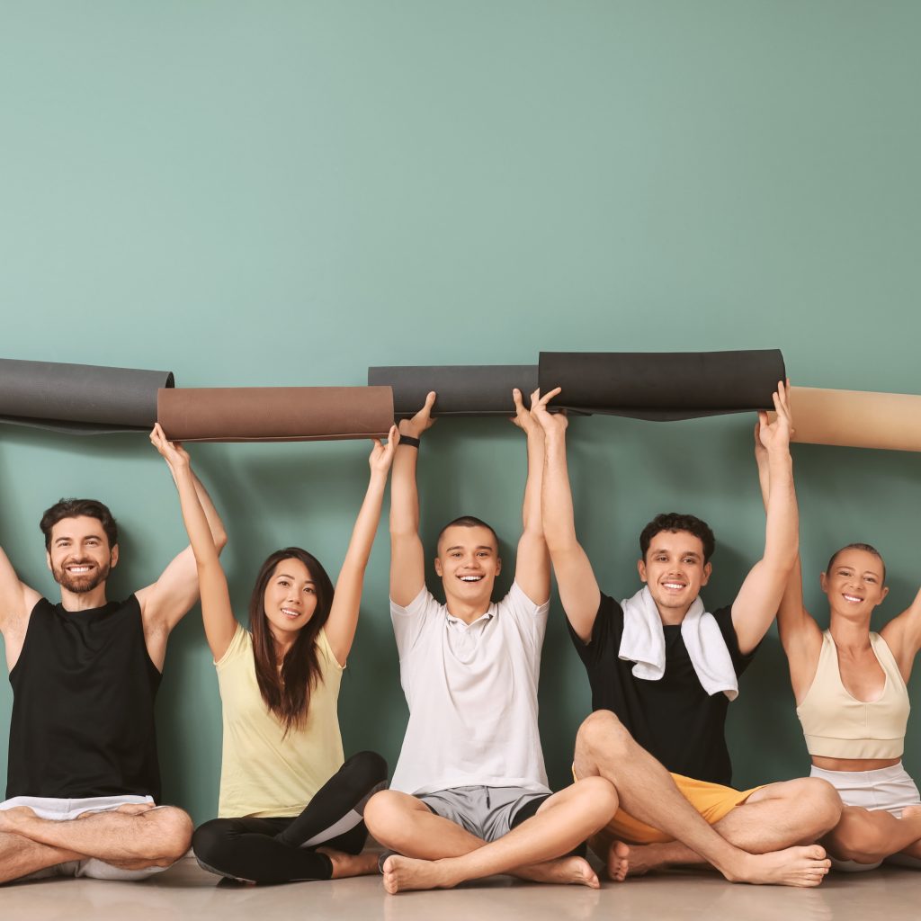 Happy group of yoga students holding yoga mats after class – fun and welcoming yoga classes in Newbury at Embrace Wellness One-to-one yoga session with private yoga teacher Manlee at Embrace Wellness in Newbury, Berkshire