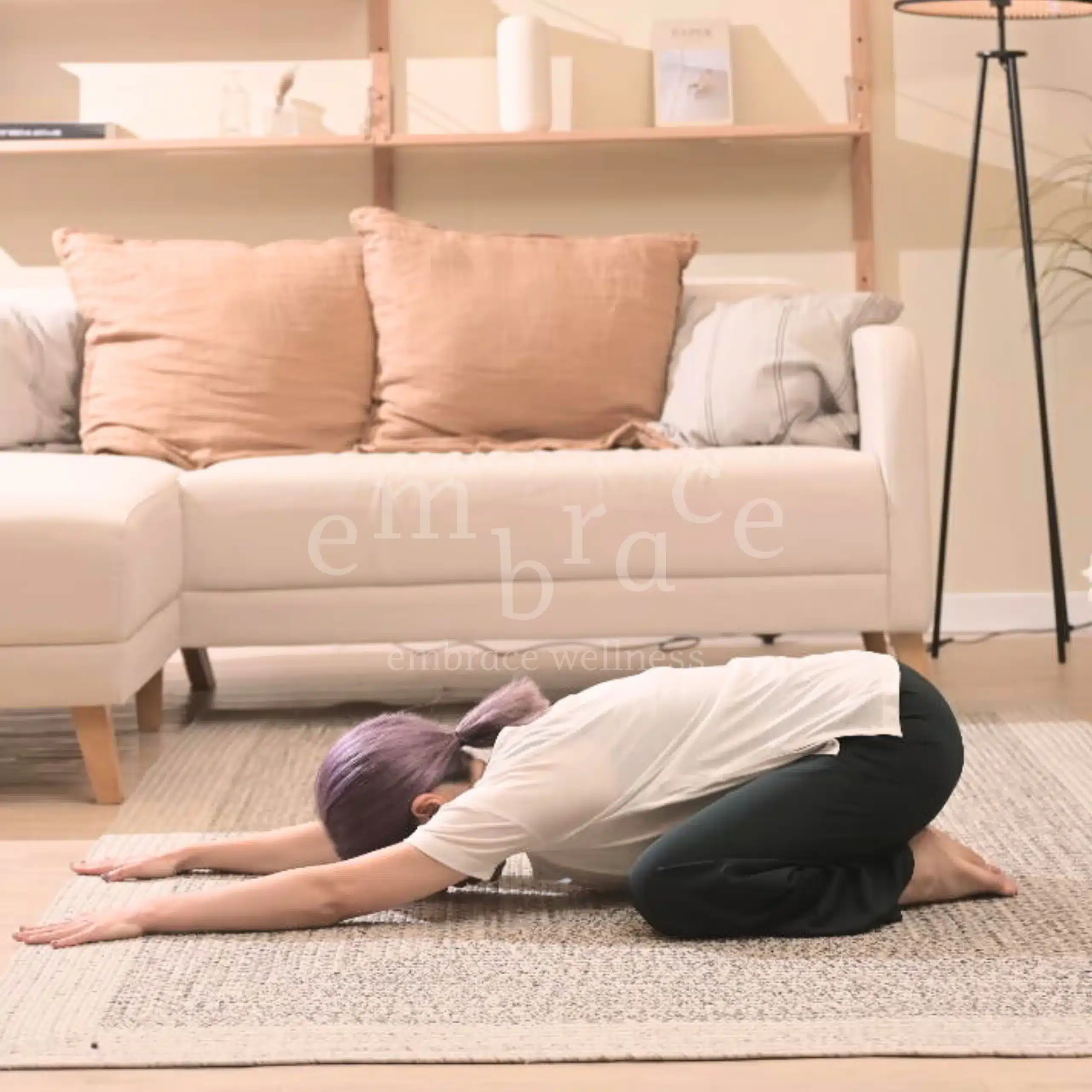 Manlee W, a yoga teacher from Newbury Berkshire, seated in a childs pose, showing a blend of mindful movement and stillness in a warm, calming studio setting.