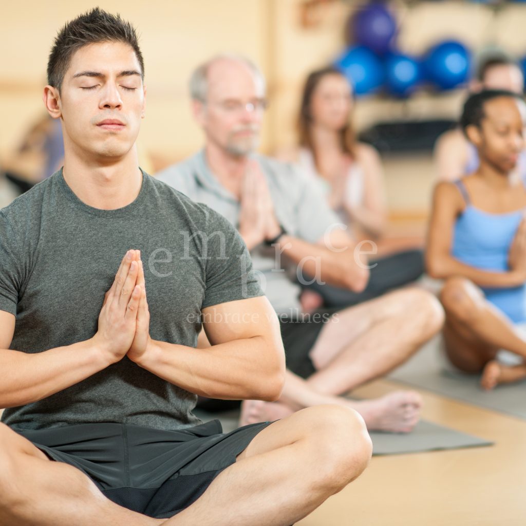 Yoga Class Newbury Timetable at Embrace Wellness with Manlee W. A group of yoga participants seated in meditation, prayer hands, focusing on breath and mindfulness in a calm studio environment in Newbury, Berkshire.