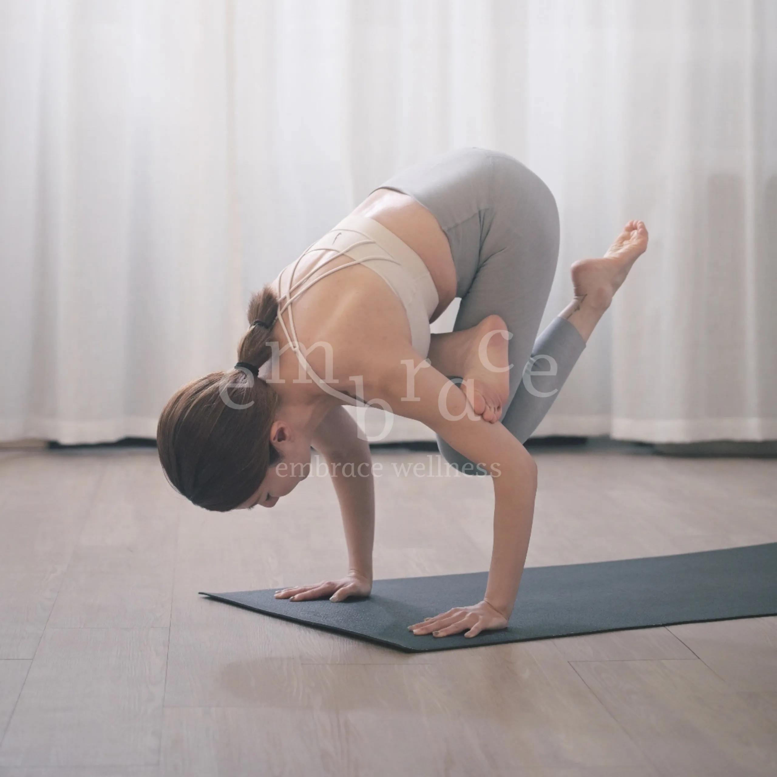 Woman balancing in crane arm balance pose on a yoga mat – Warrior Heart power yoga classes at Embrace Wellness Newbury