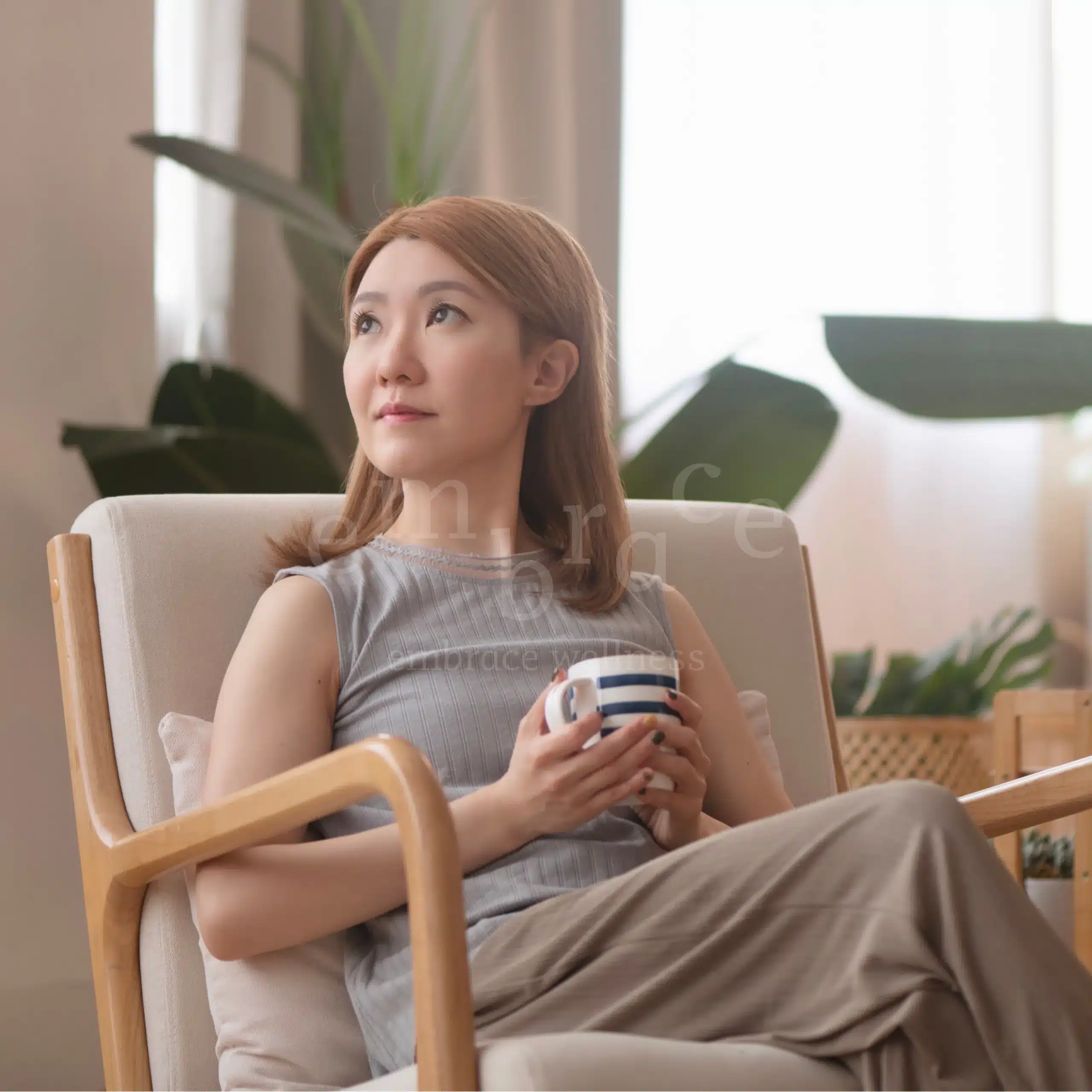 Manlee W, holistic wellness coach and yoga teacher at Embrace Wellness Newbury Berkshire, sitting mindfully with tea in a calm plant-filled room