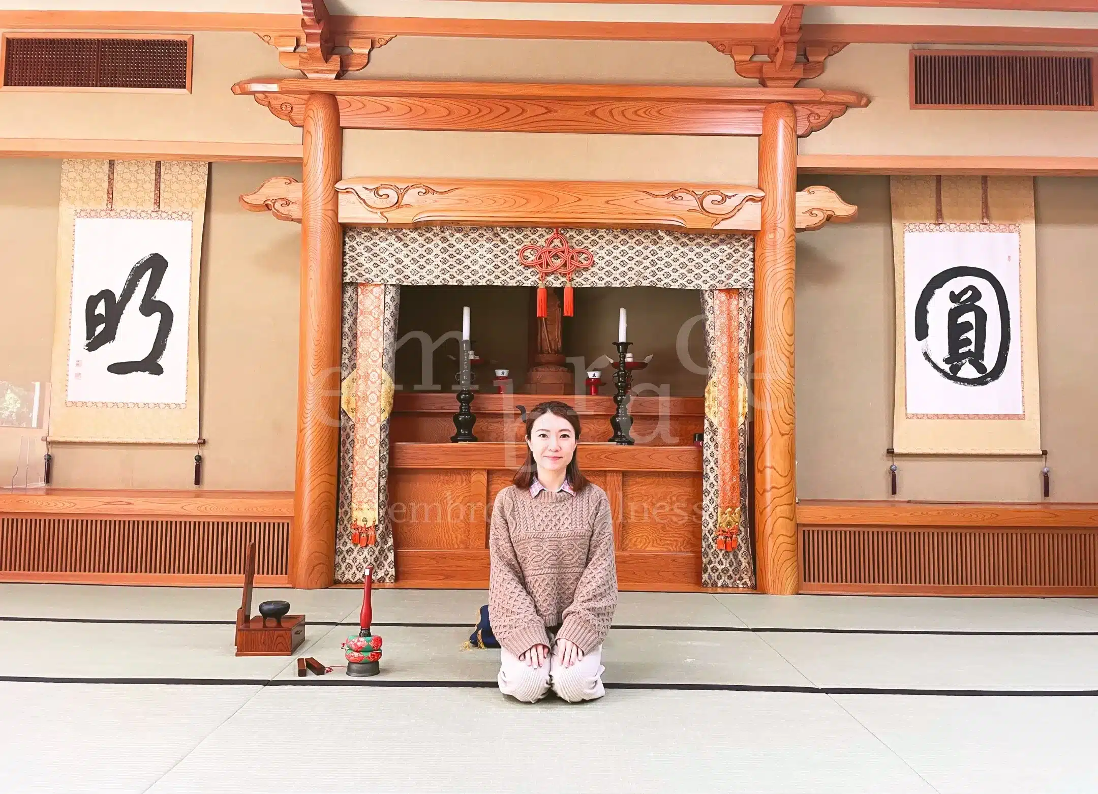 Wellness coach Manlee kneeling inside HouKouji Temple during a ZEN temple stay in Japan, seated before a traditional Buddhist altar and calligraphy scrolls