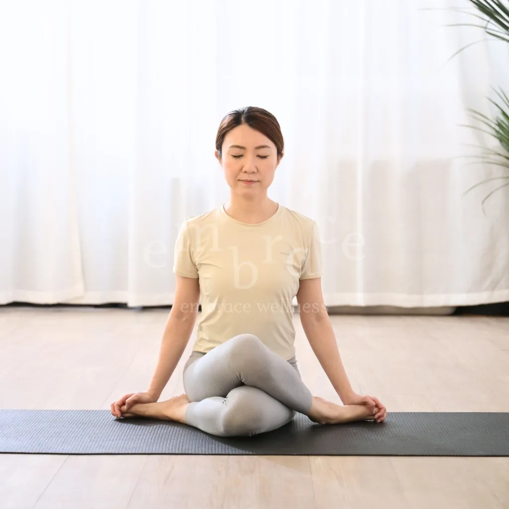 A yoga practitioner seated in Sukhasana with eyes gently closed in peaceful mindful meditation during a Yoga for Beginners class in Newbury with Embrace Wellness by Manlee W