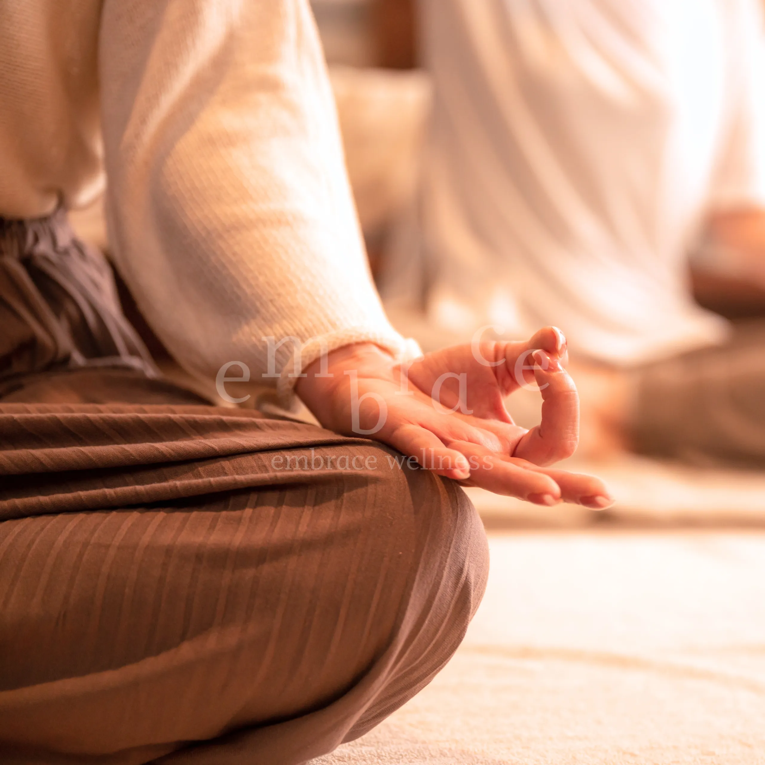 A close-up of hands forming Gyan mudra resting on crossed legs during a mindful yoga and breathwork session at a Yoga for Beginners class (Hatha Yoga) in Newbury, Berkshire, with Embrace Wellness by Manlee W